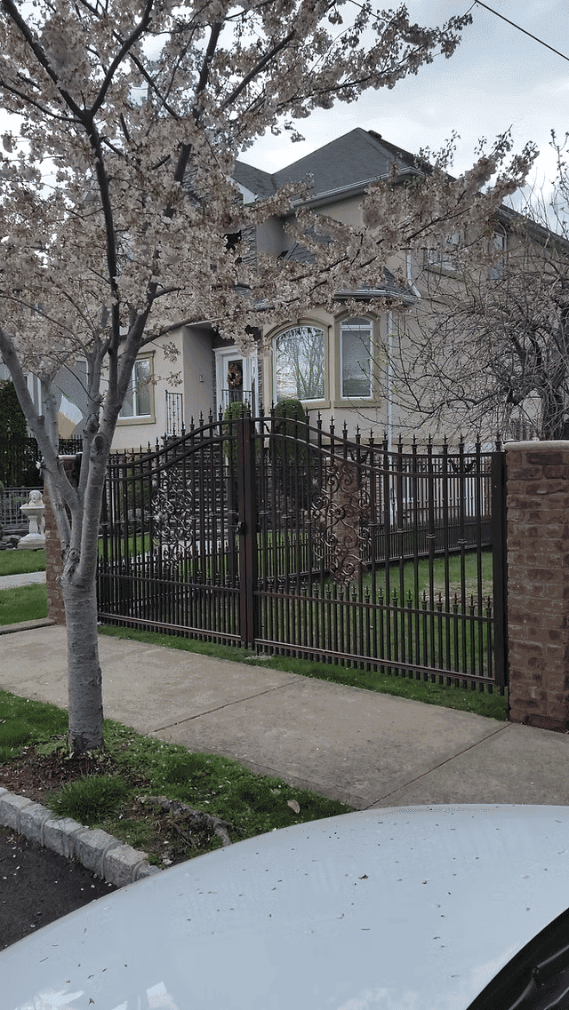 Springtime view of a house with a decorative iron gate and blooming flowering tree.