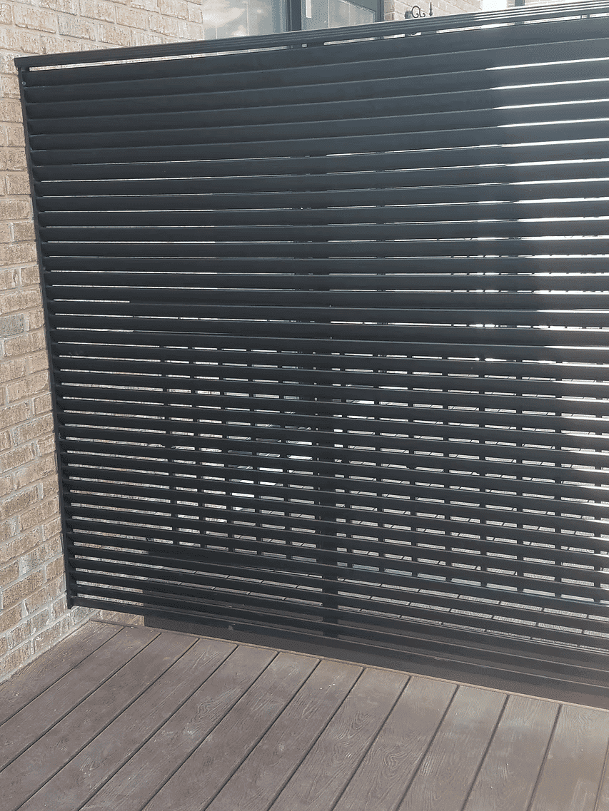 Black vertical slatted screen on a brick wall, enhancing outdoor privacy and aesthetics.