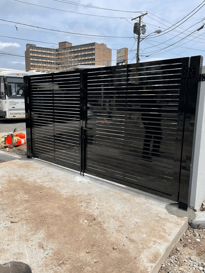 Modern black slatted gate at an urban entrance, providing security and aesthetics.