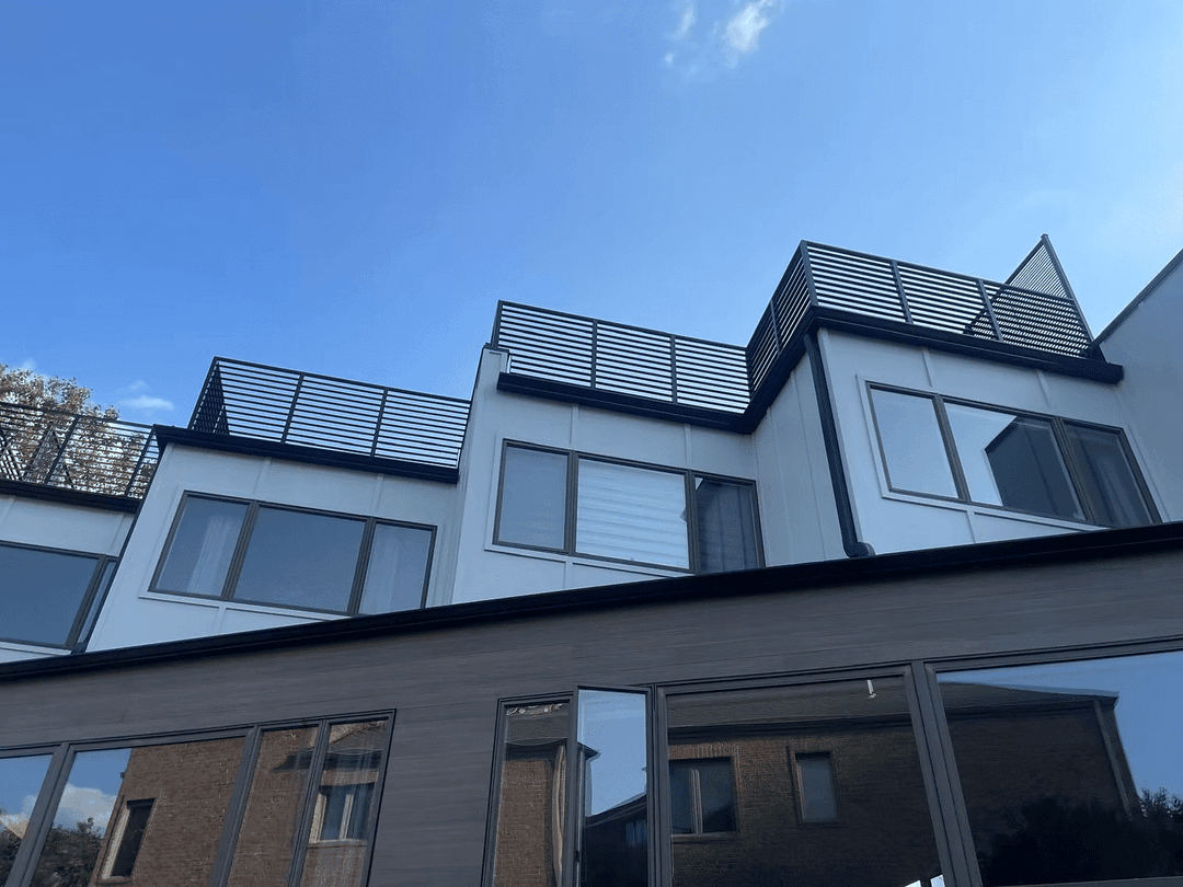 Modern multifamily building with sleek design and rooftop terrace under a clear blue sky.