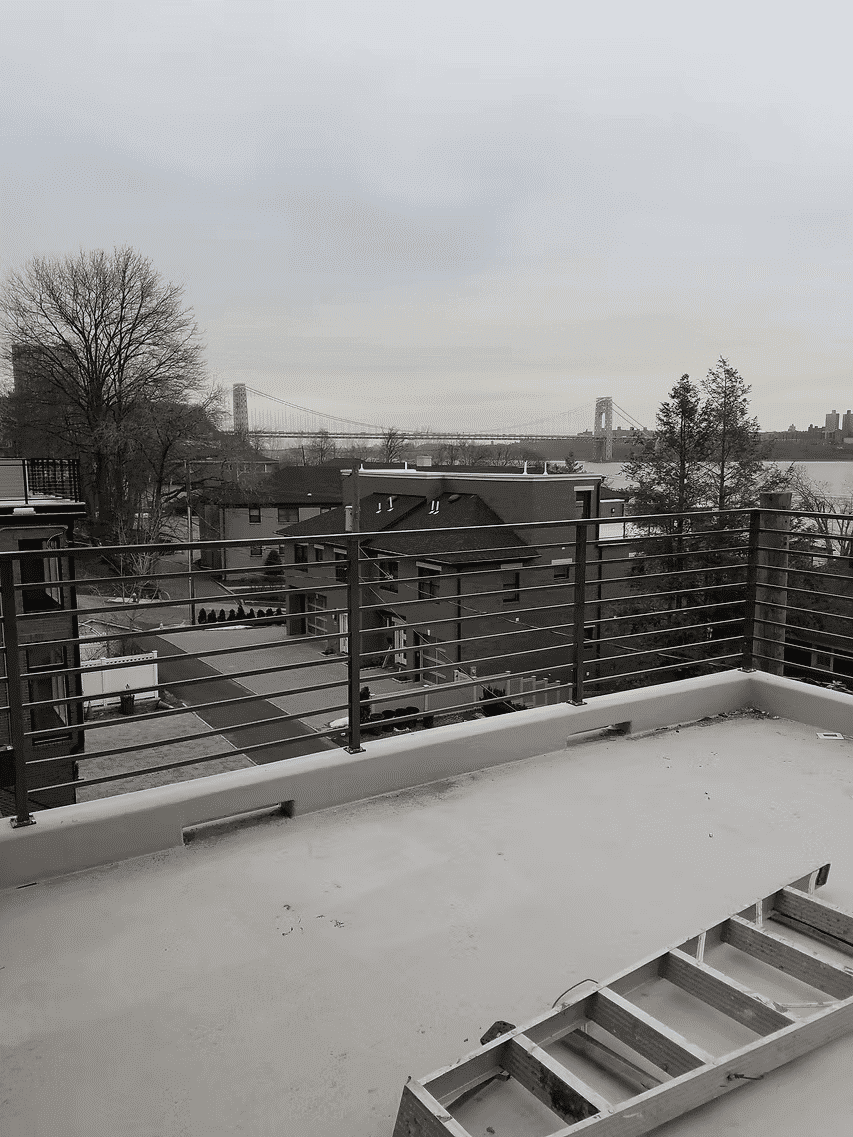 Rooftop view of the George Washington Bridge with residential buildings and cloudy sky.