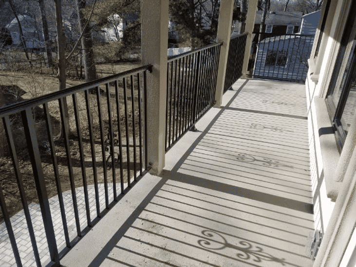 Spacious balcony with wrought iron railings and shadow patterns on the floor.