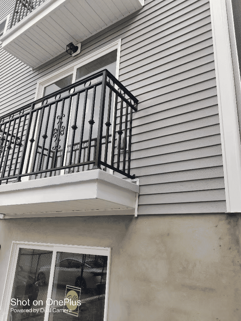 Modern building exterior featuring a balcony with iron railings and textured siding.