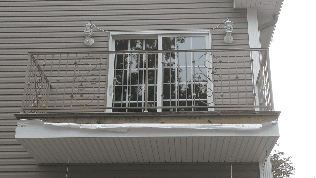 Balcony with decorative railing and large windows on a house exterior.