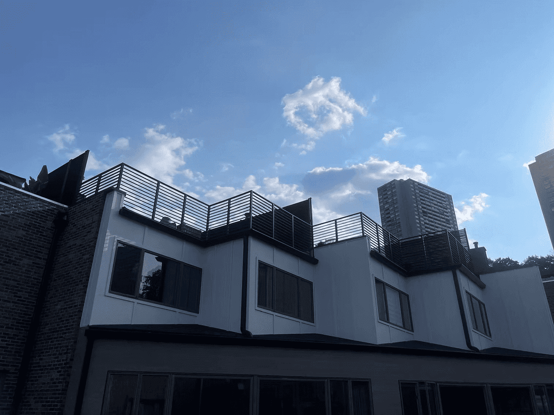 Modern residential building with rooftop terrace against a clear blue sky.