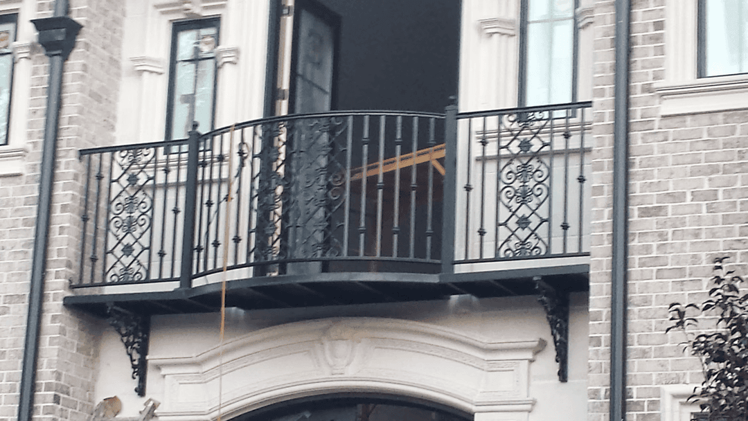 Elegant wrought iron balcony railing on a stylish brick building façade.