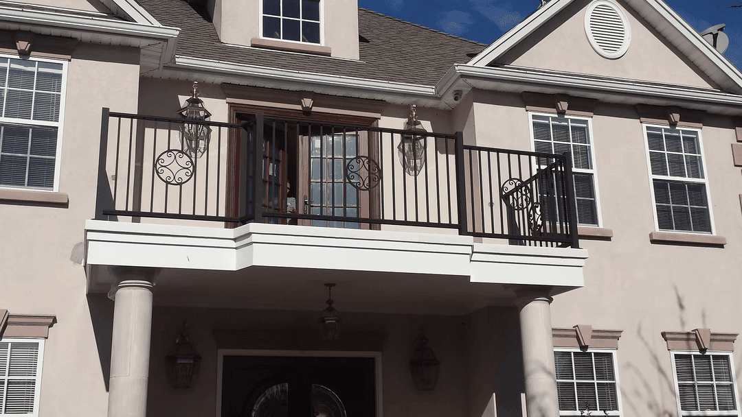 Elegant two-story home with decorative balcony, double doors, and stylish outdoor lanterns.