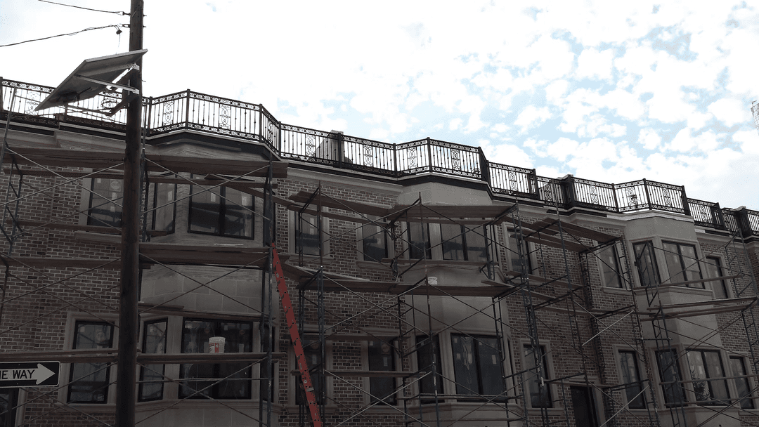 Newly constructed apartment building with scaffolding under a cloudy sky.