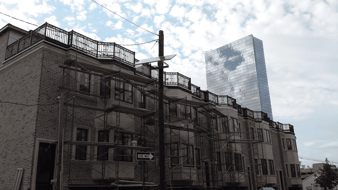 Newly constructed building with scaffolding and modern skyscraper in the background.