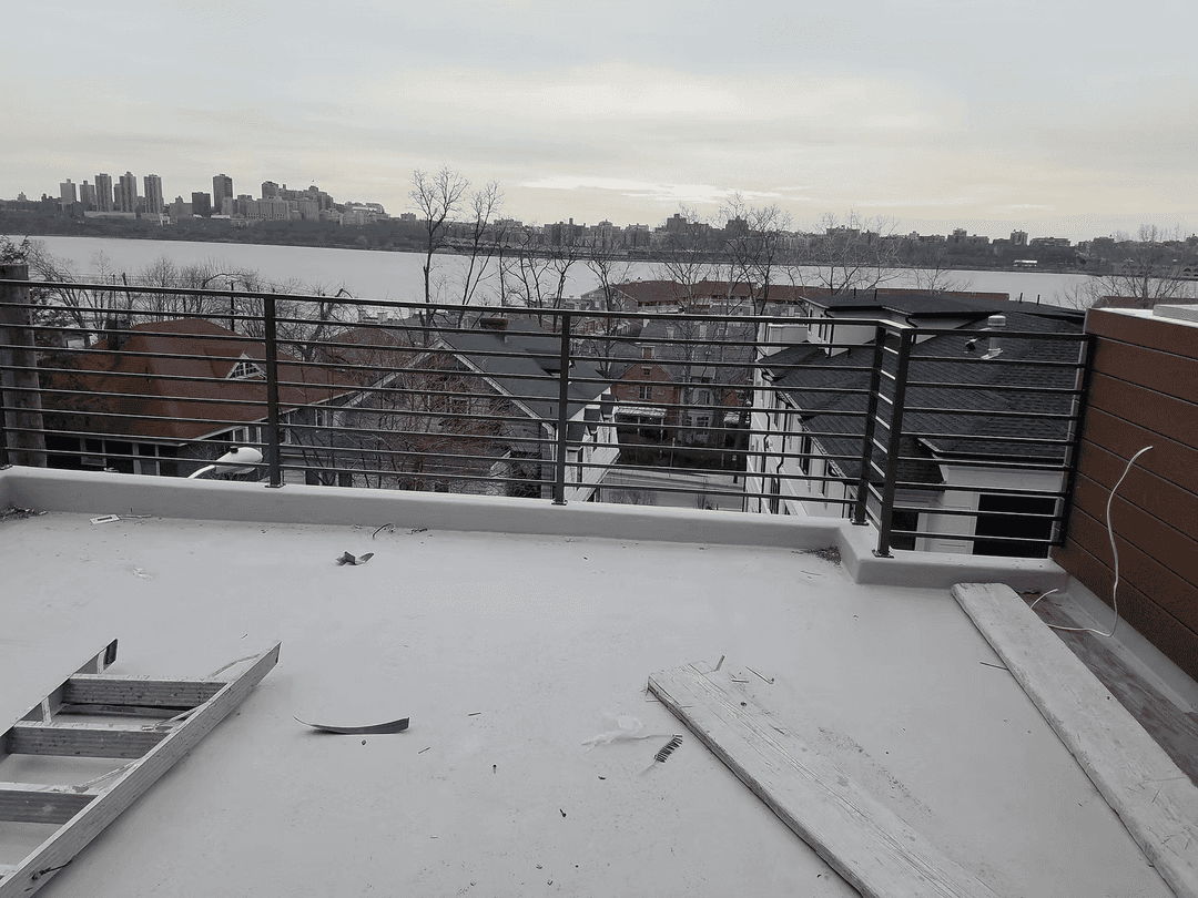 Rooftop view of city skyline and waterfront with construction materials on the terrace.