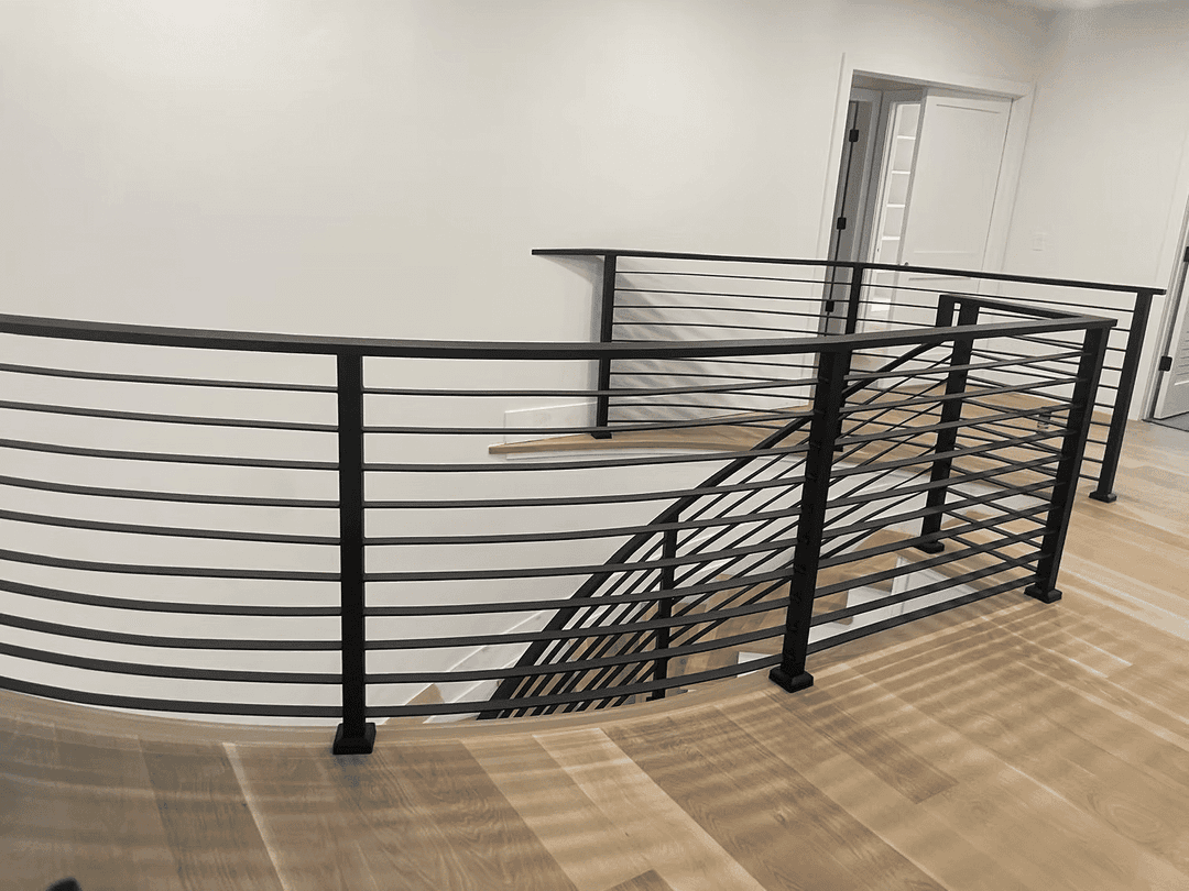 Modern black metal railing with horizontal slats on a curved staircase landing.