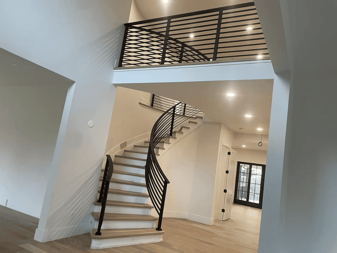 Modern spiral staircase with black railing in contemporary home interior. Bright lighting.