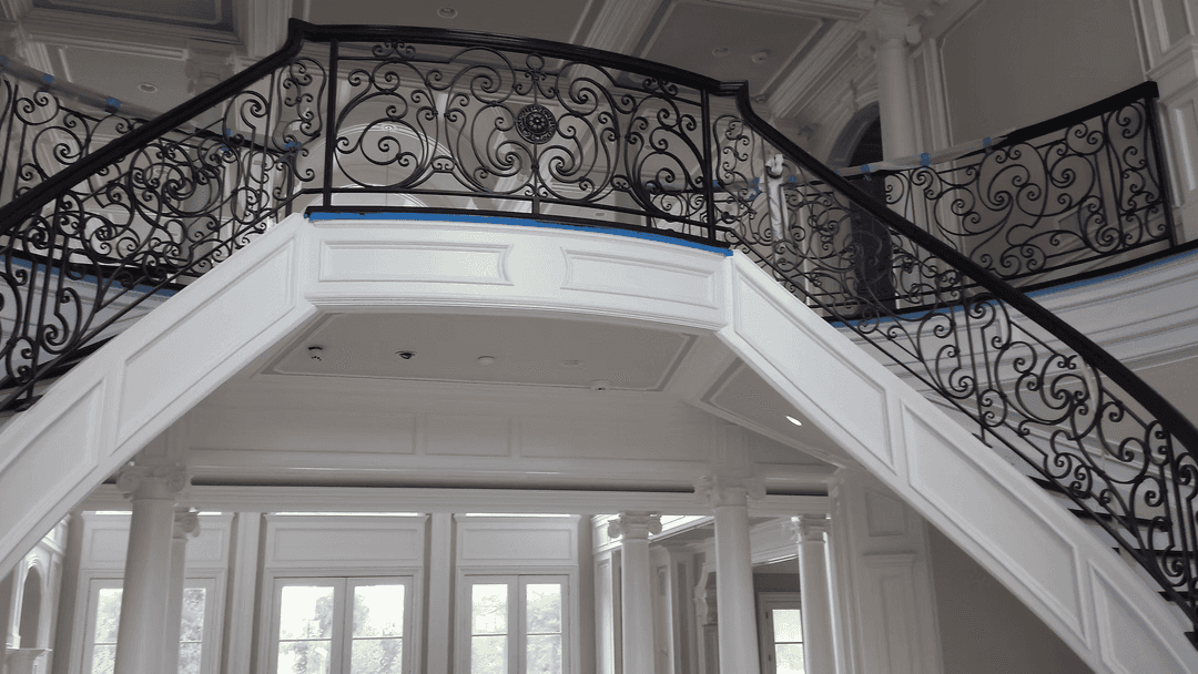 Elegant black wrought iron railing on a curved staircase in a luxurious interior space.