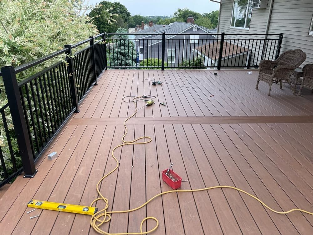 Deck installation in progress with tools and materials on a spacious outdoor balcony.