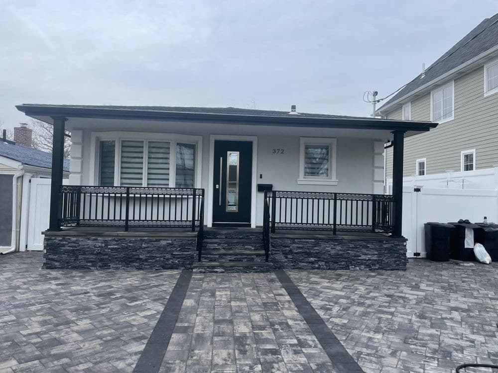 Modern house exterior with black railing, stone steps, and gray paver driveway at 372.