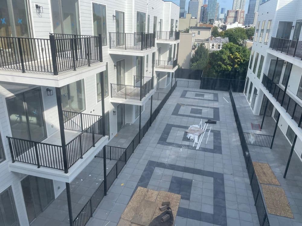 New modern apartment complex with balconies and a shared outdoor courtyard in a city setting.