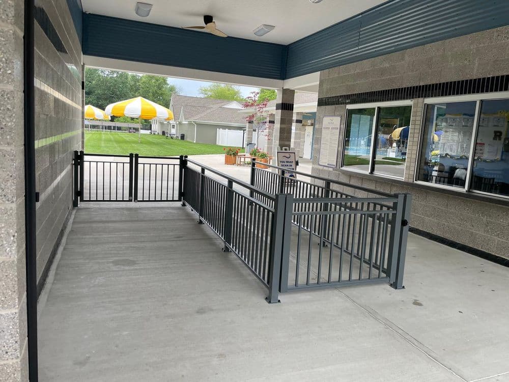 Accessibility ramp leading to a recreational area with yellow-striped umbrellas in the background.