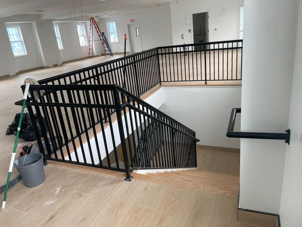Modern indoor staircase with black railings in a partially finished building interior.