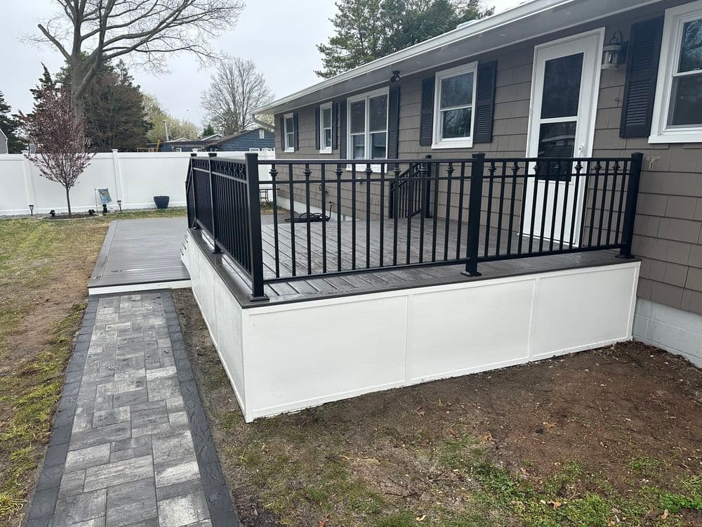 Modern home exterior with a black railing deck and landscaped pathway. Ideal for outdoor living.