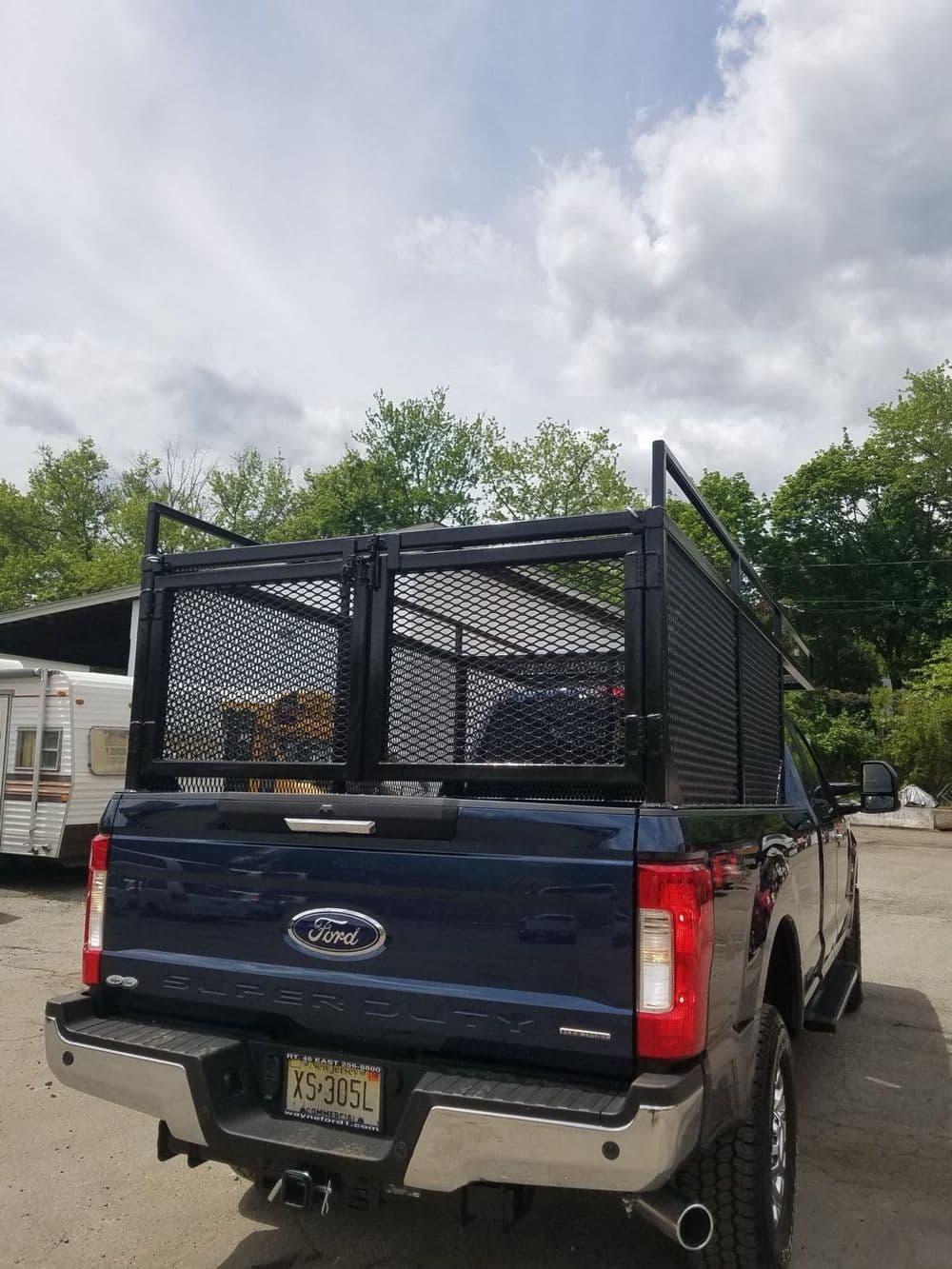 Ford truck with a metal mesh bed cover parked outdoors under cloudy skies.