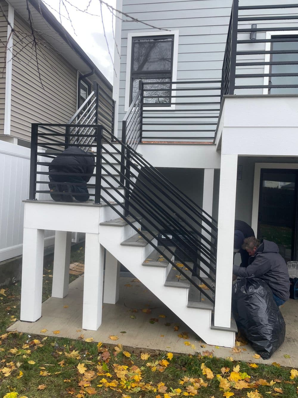 Workers installing modern black railings on a staircase of a newly constructed home.