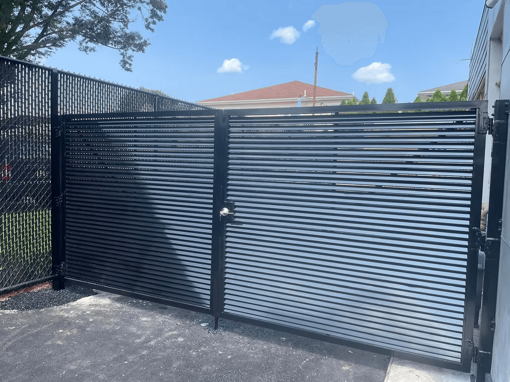 Modern black slatted gate on a clear day, showcasing sleek design and security features.