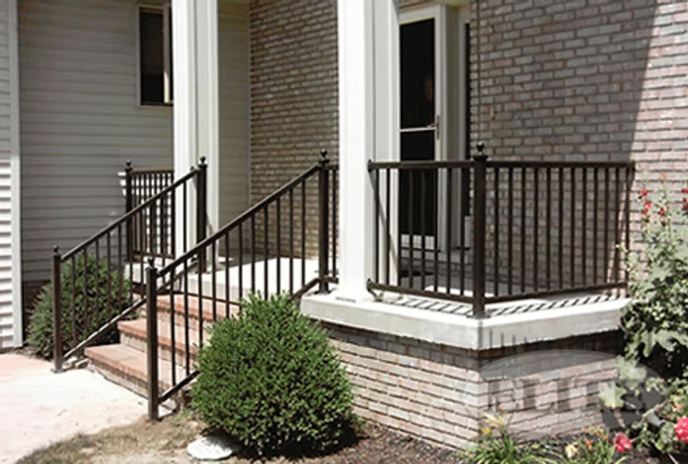 Handrails on brick steps leading to a front porch with decorative plantings.