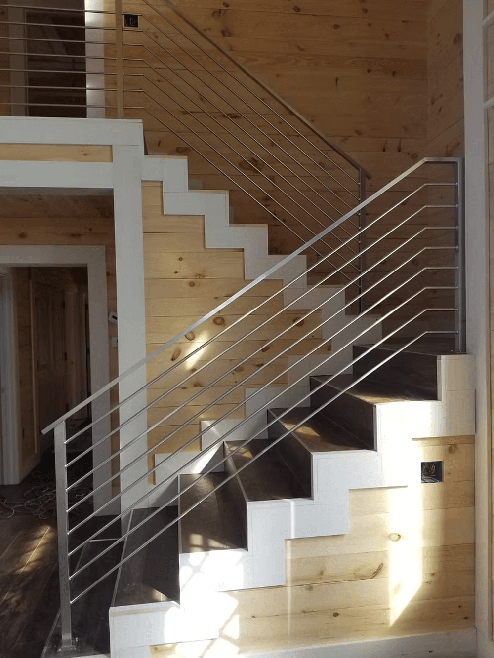 Modern wooden staircase with metal railing in a well-lit interior setting.