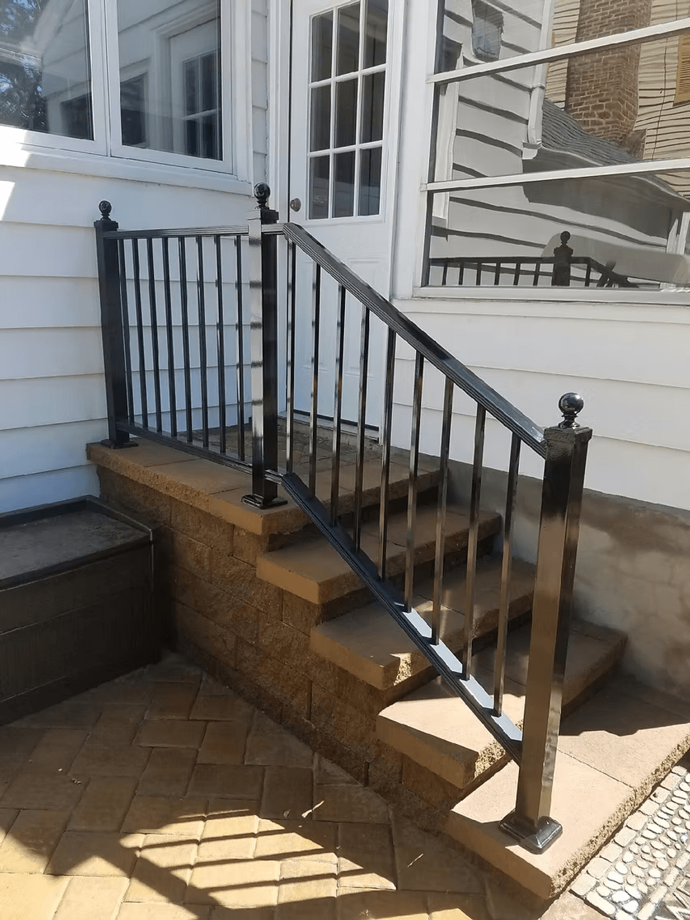 Black metal railing on stone steps leading to a house entrance, enhancing safety and design.