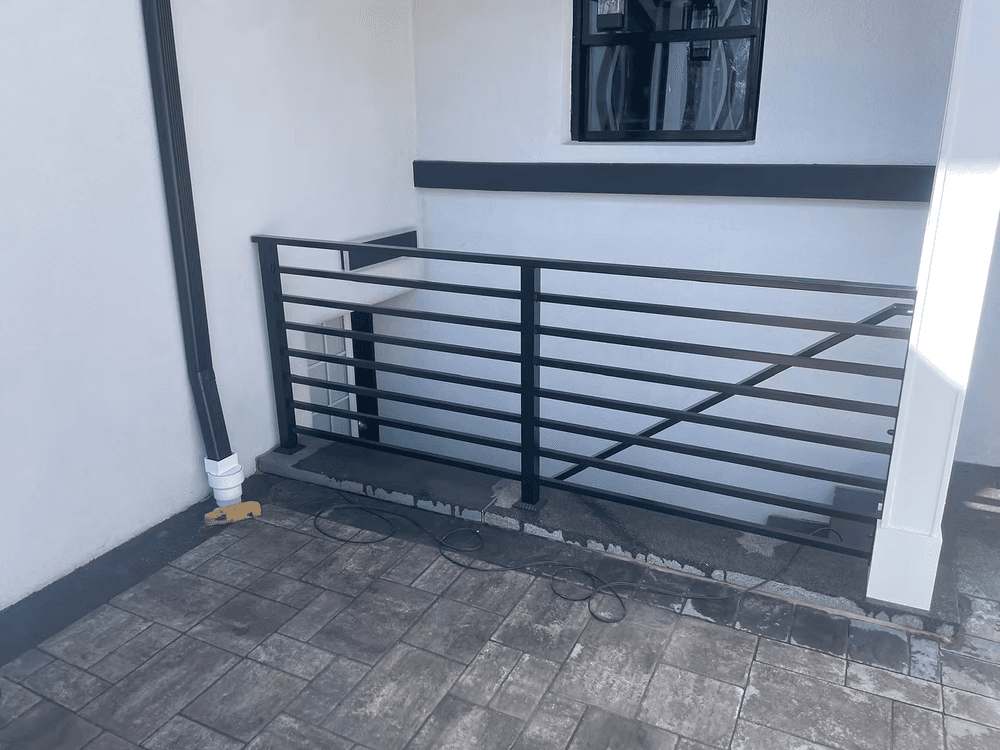 Modern outdoor railing design with black metal bars and concrete flooring, enhancing safety.
