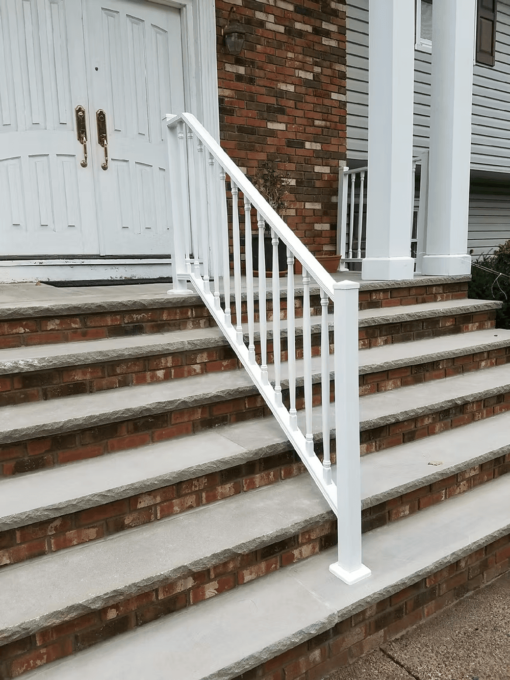 White railing on brick steps leading to a front door of a house, enhancing safety and aesthetics.