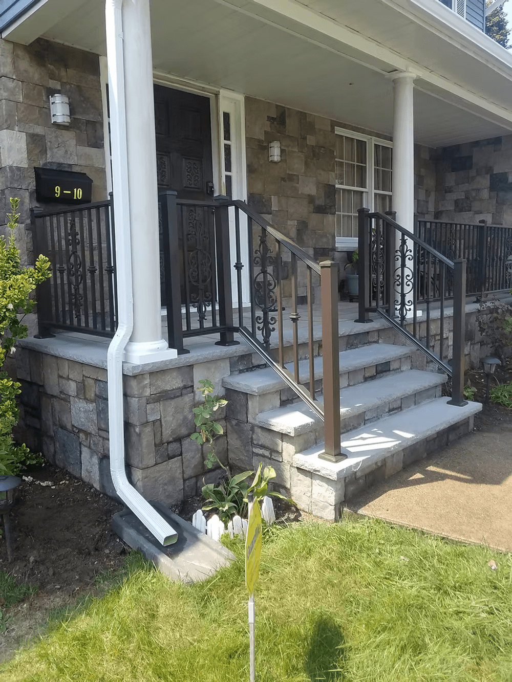 Front porch with stone facade, elegant railings, and landscaping details. House number visible.