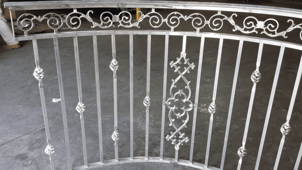 Decorative wrought iron railing with intricate designs and smooth finish on a concrete floor.