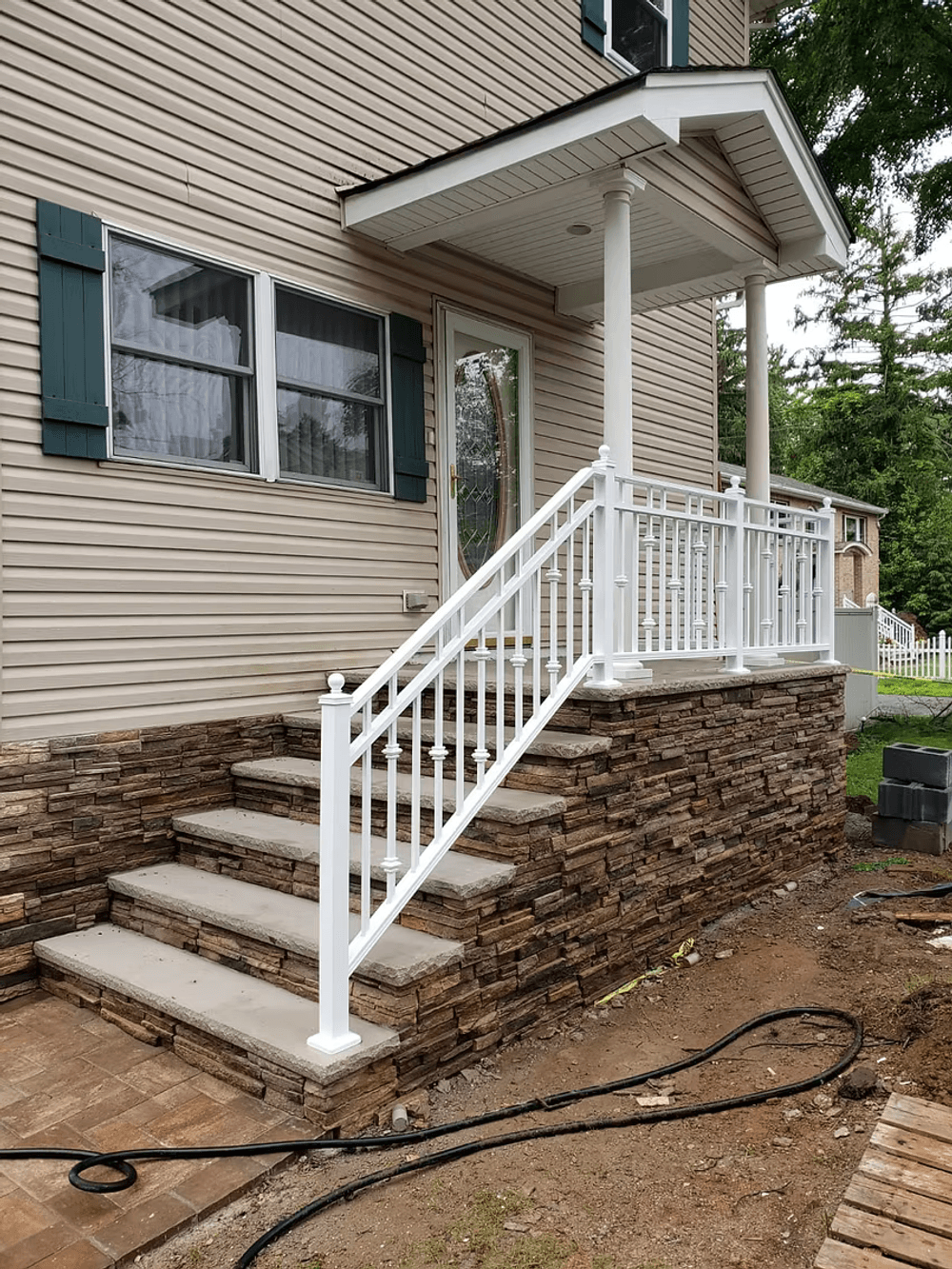 White railing on stone steps leading to a suburban home's entrance.