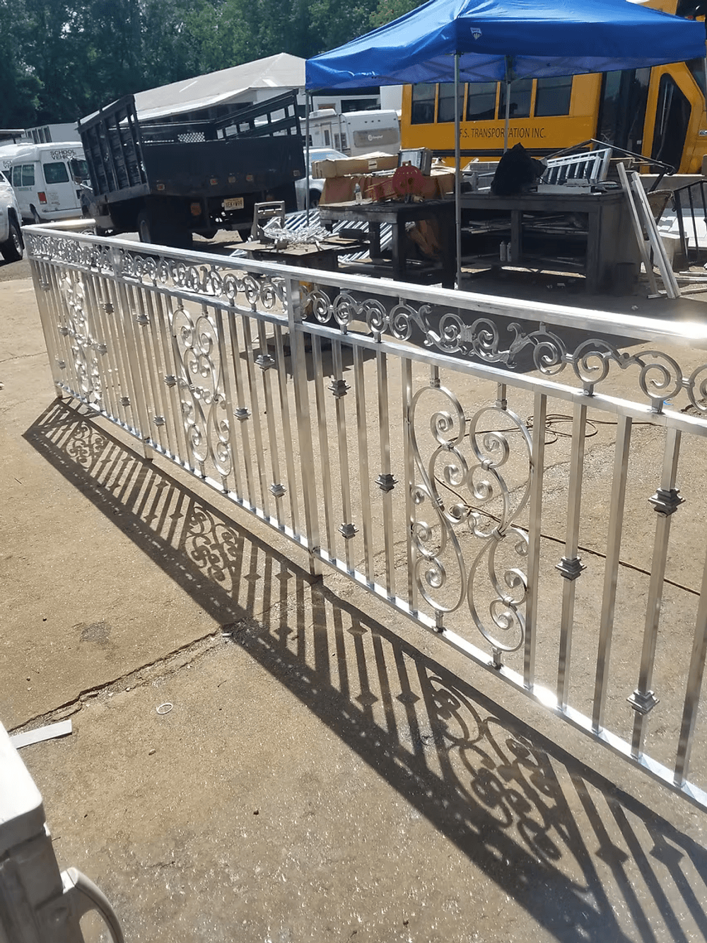 Decorative aluminum fence with ornate design, casting shadows on a concrete surface.