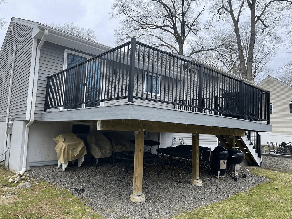 Deck with black railing attached to a house, overlooking outdoor storage and yard area.