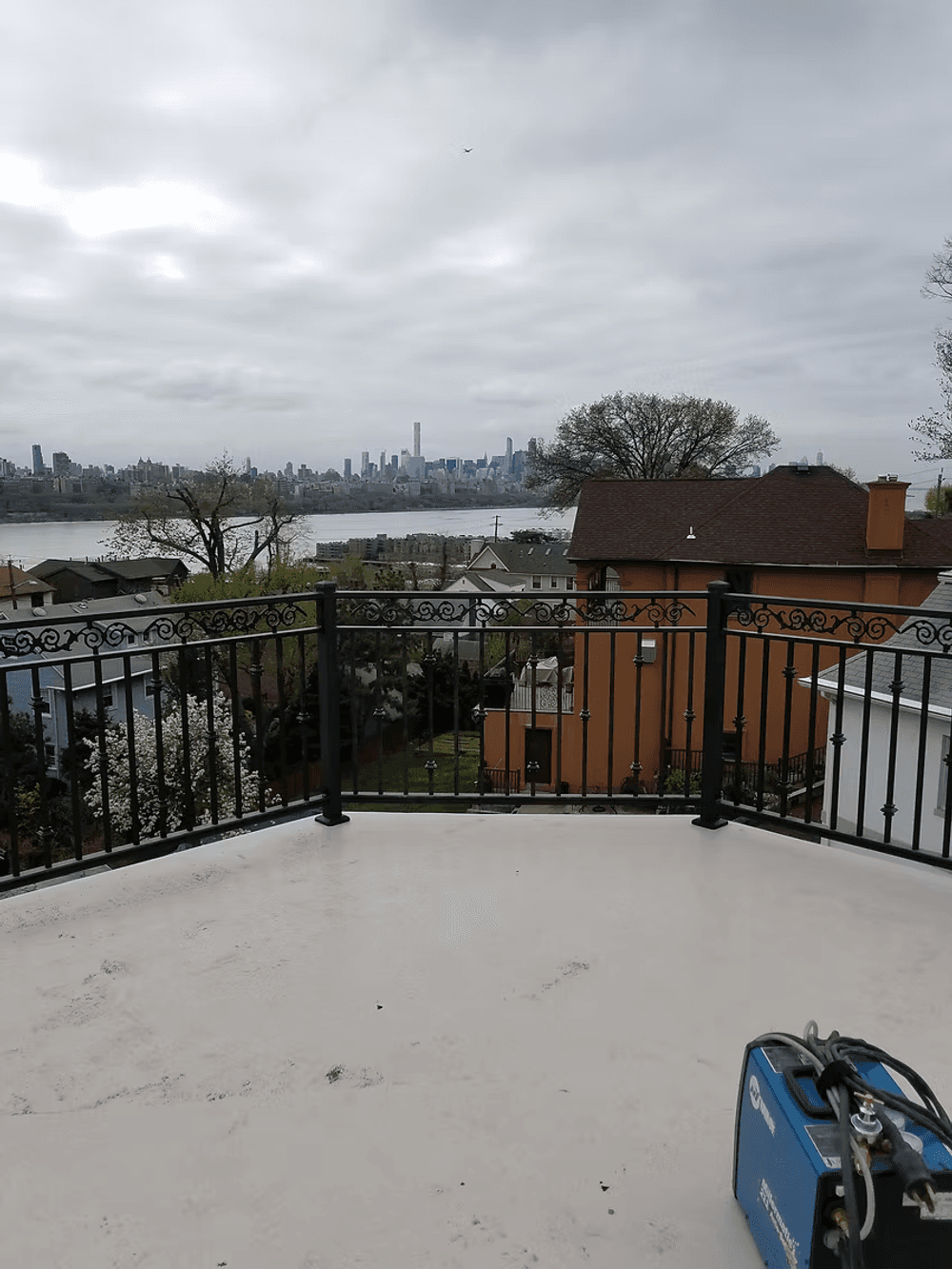 Scenic city view from a balcony overlooking rooftops and a river with cloudy skies.