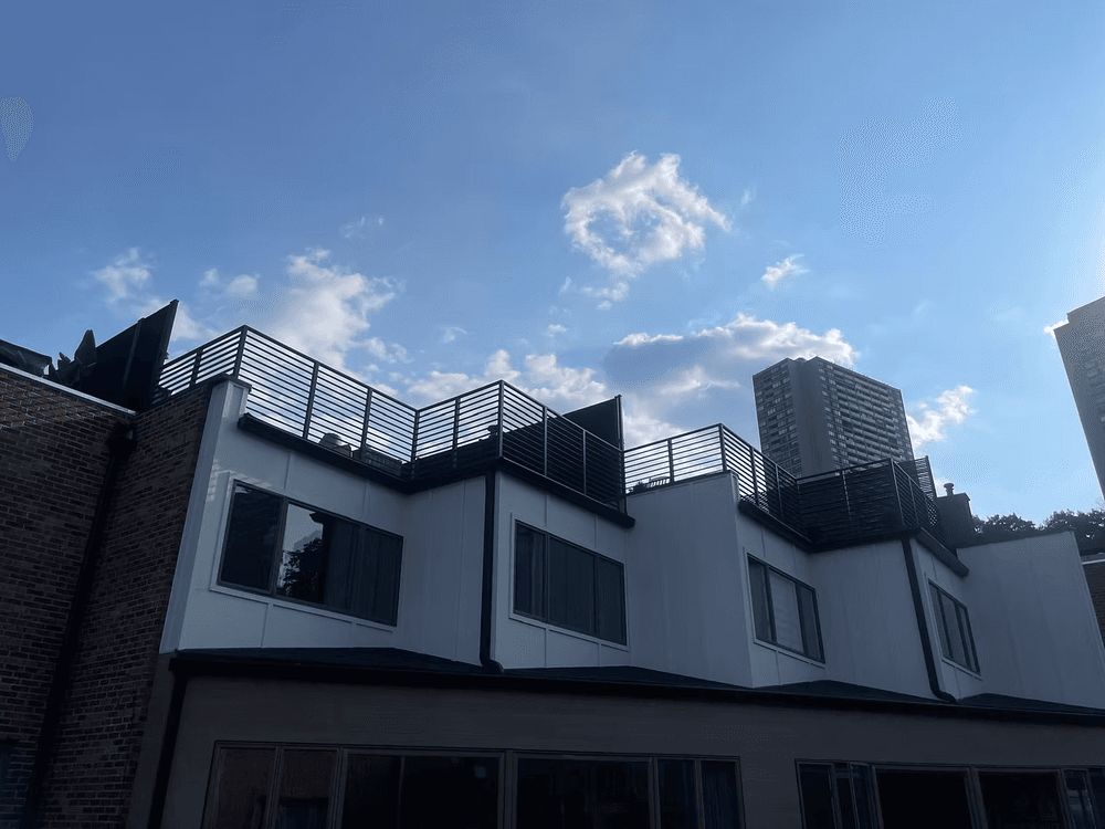 Modern building with a rooftop terrace against a clear blue sky and city skyline.