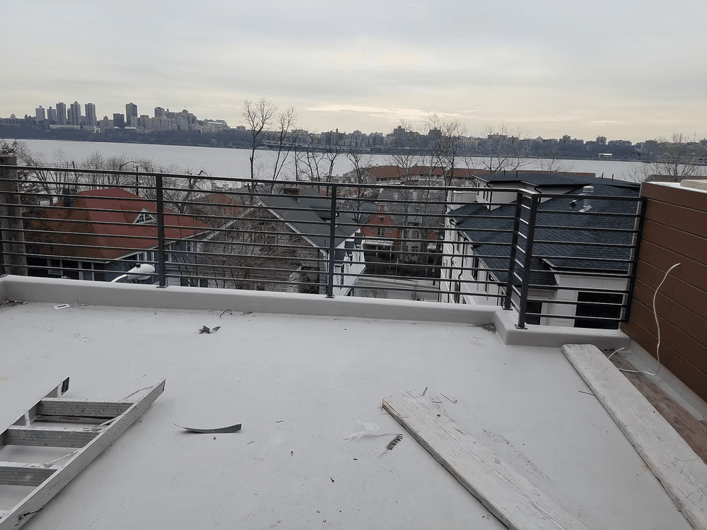 View of a rooftop terrace overlooking the river and city skyline, with construction materials visible.