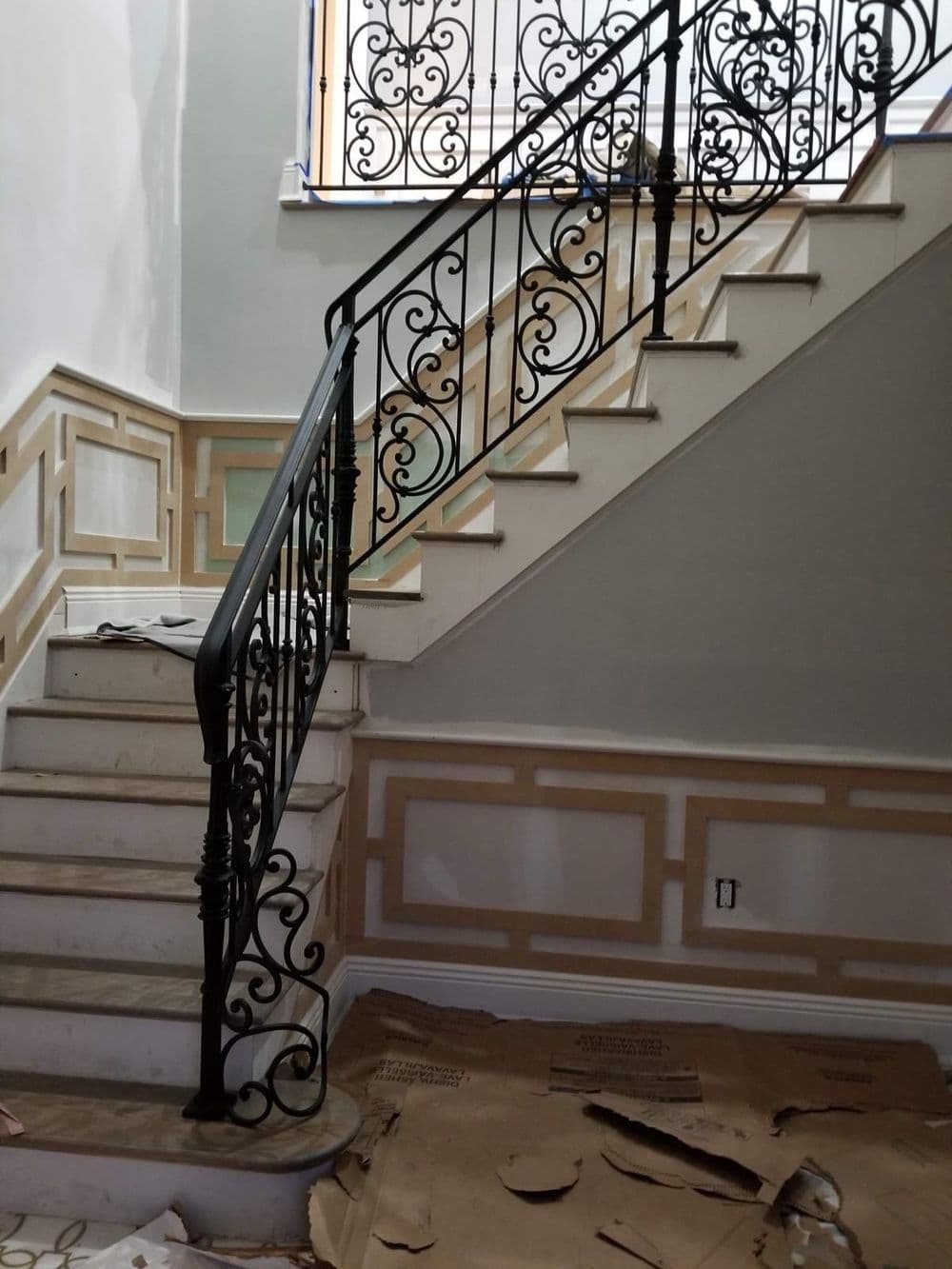 Elegant black wrought iron staircase railing with intricate designs, newly renovated home interior.