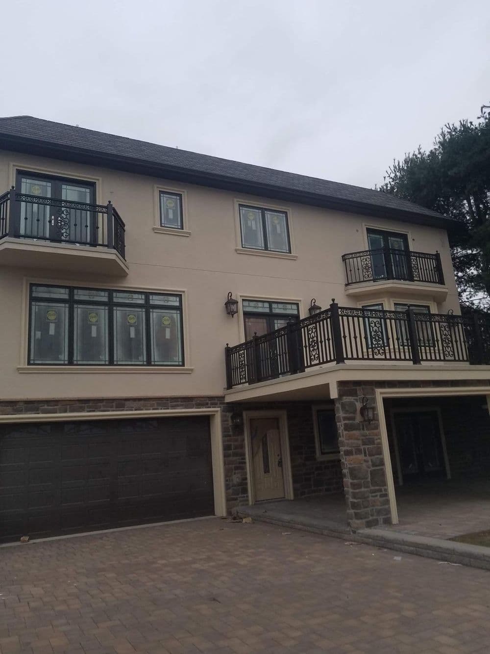 Modern multi-story house with stone accents and balconies, featuring large windows.
