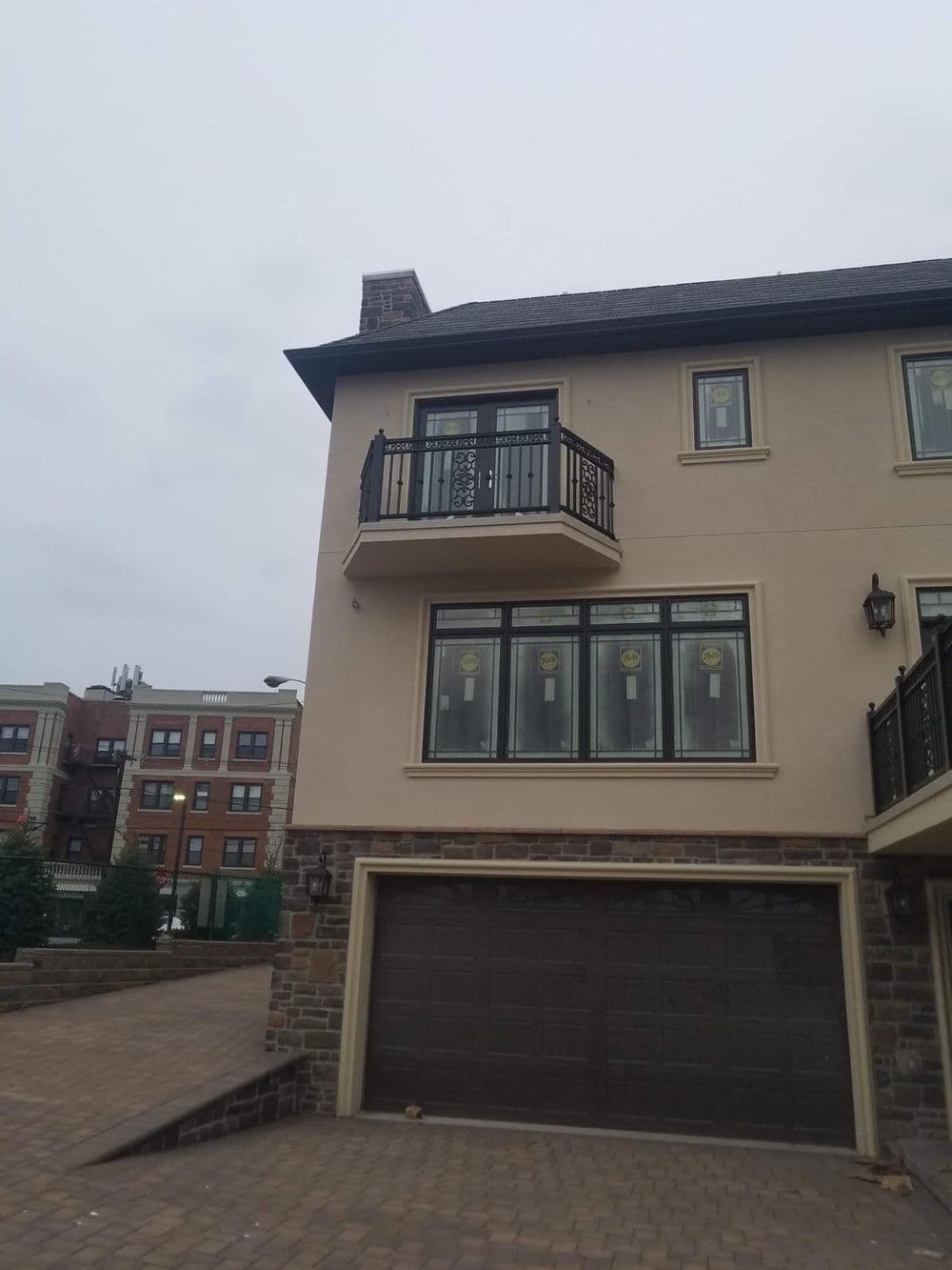 Two-story house with a balcony and stone accents, set in an urban neighborhood.