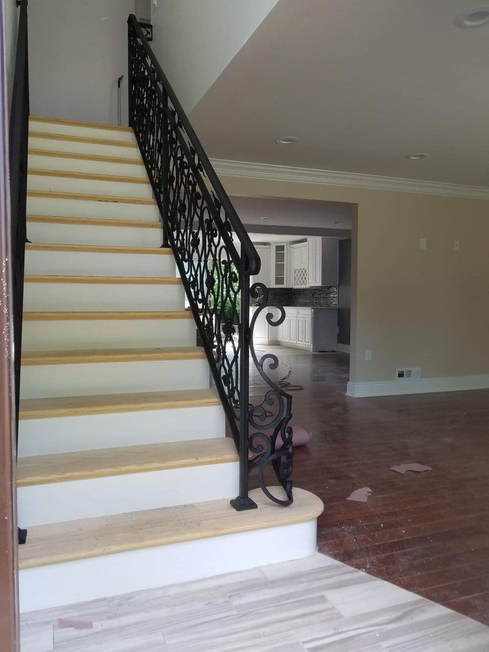 Elegant staircase with decorative black railing, leading to a spacious, newly renovated room.
