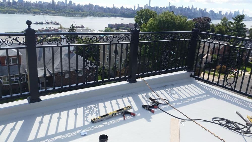 Rooftop terrace with a view of a city skyline and rivers, featuring ornate black railing.