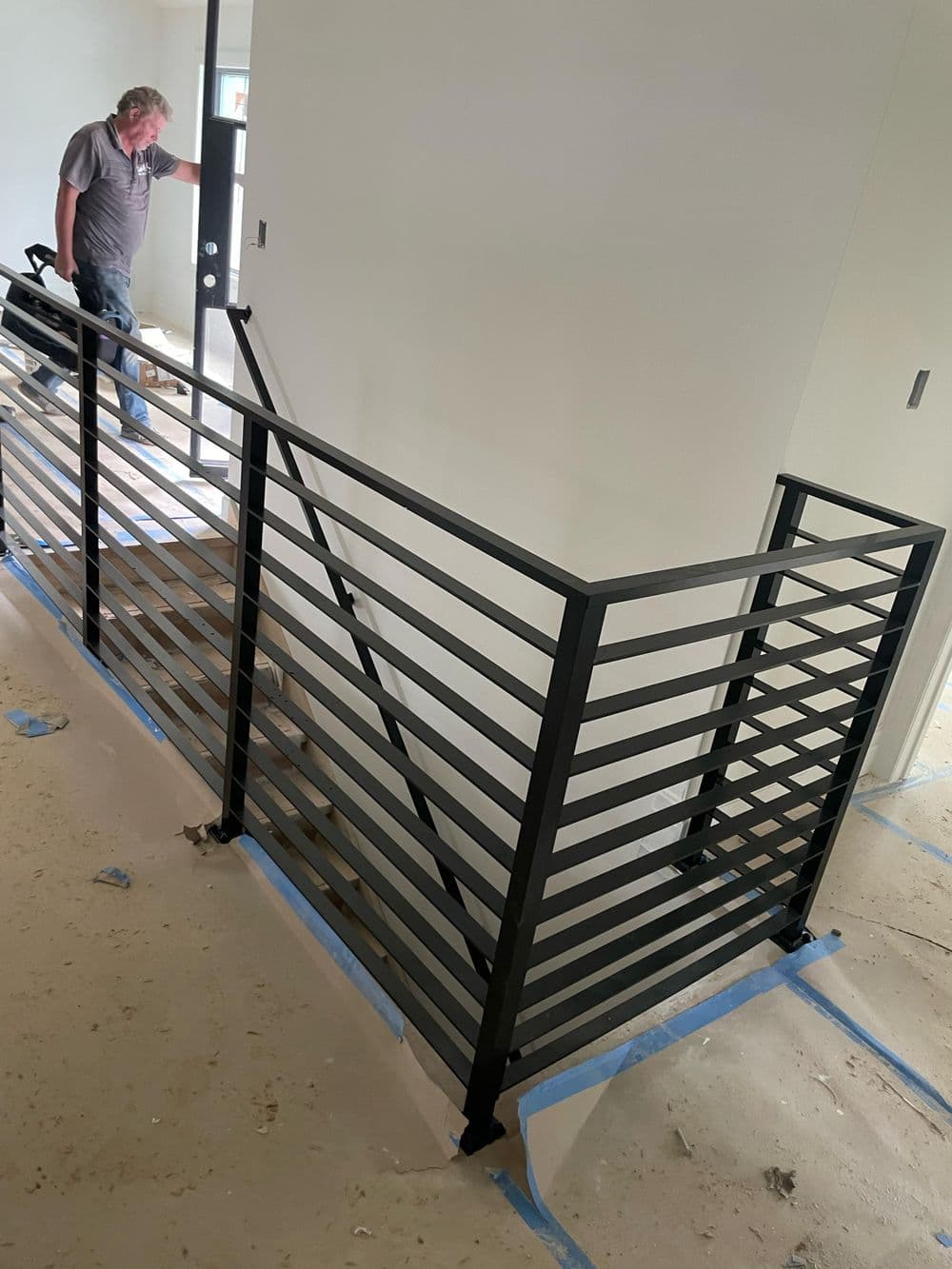 Modern black metal railing installation in a spacious interior stairwell.