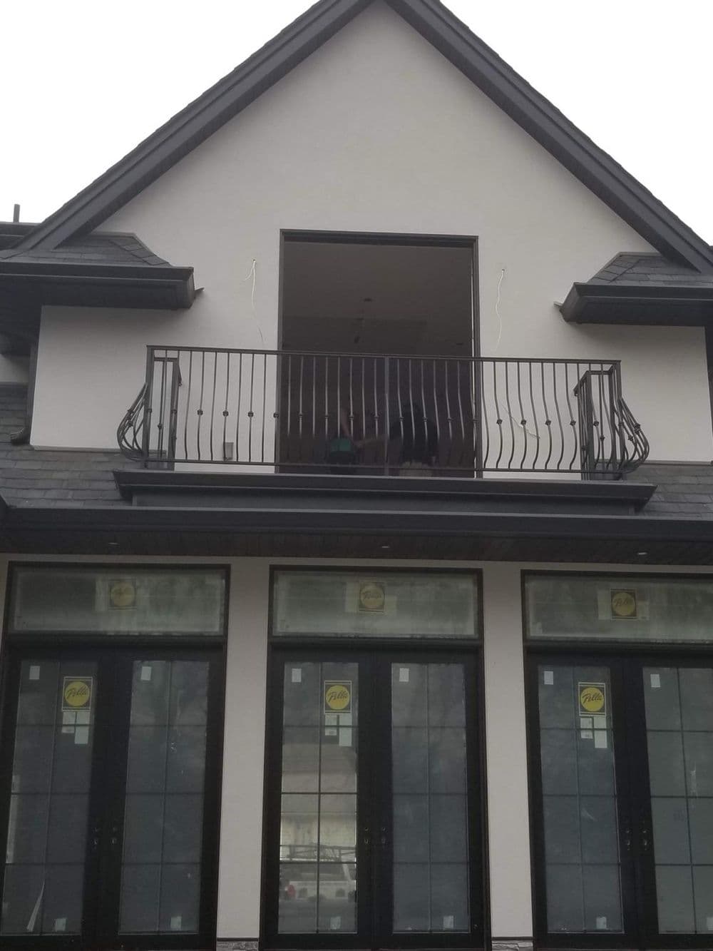 Modern home exterior with a large balcony and French doors, featuring sleek architectural design.