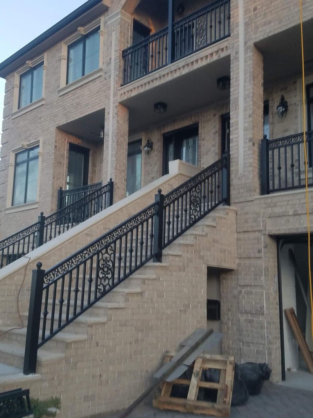 Modern brick townhouse exterior with black railings and staircase leading to the entrance.