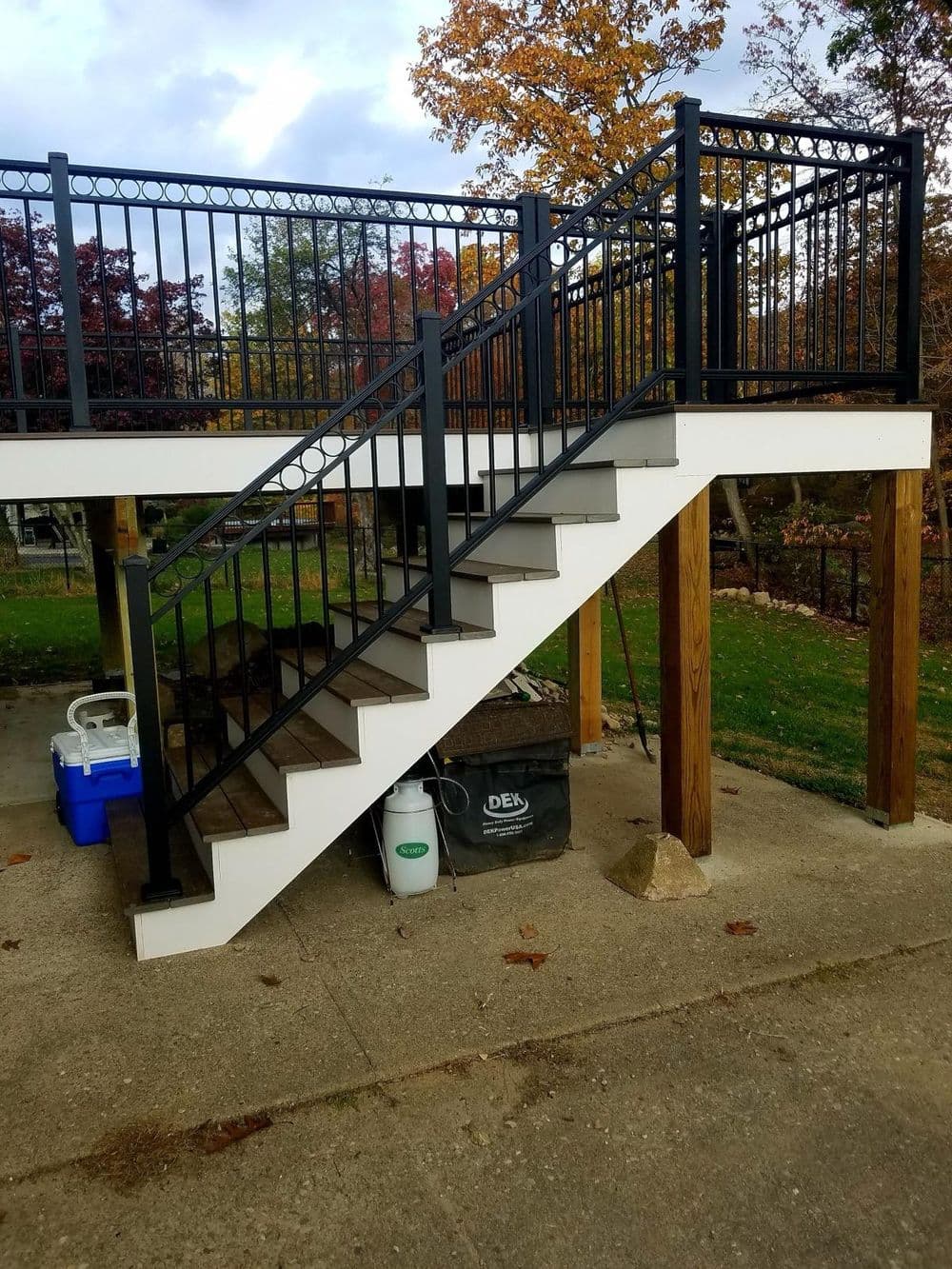 Sturdy outdoor staircase with black railing, leading to a raised deck in a landscaped area.