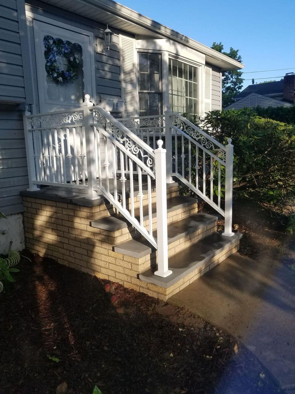 White wrought iron railings on brick steps leading to a charming home entrance.