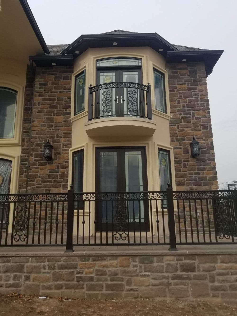 Elegant stone exterior of a modern house featuring a balcony and decorative railing.